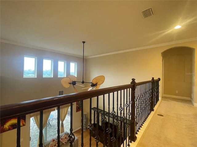 hall with baseboards, visible vents, arched walkways, crown molding, and carpet floors