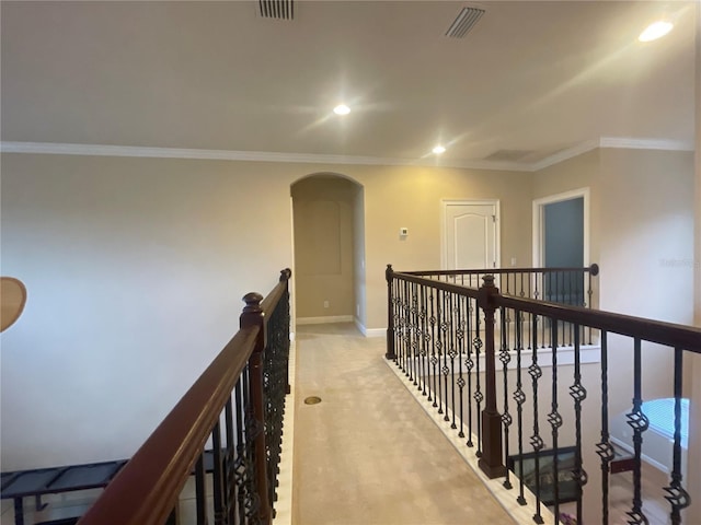 corridor with arched walkways, light carpet, visible vents, an upstairs landing, and ornamental molding