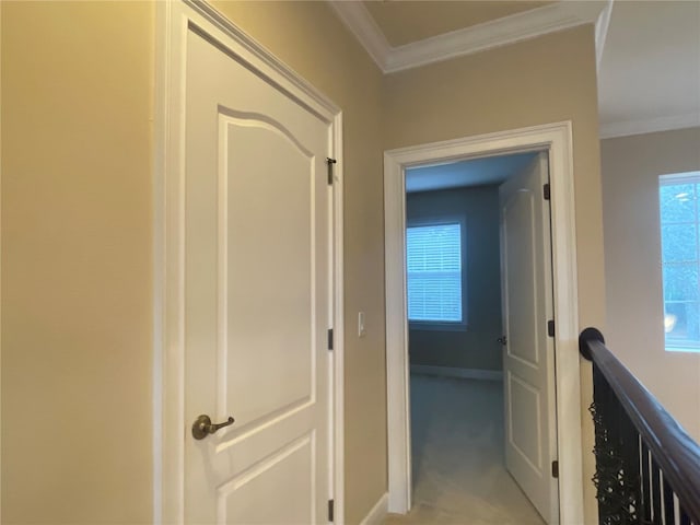 corridor featuring baseboards, crown molding, and light colored carpet