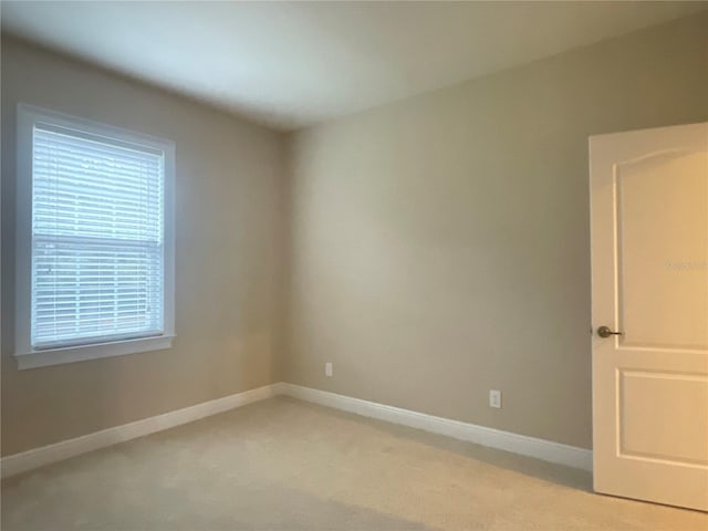 empty room with baseboards and light colored carpet