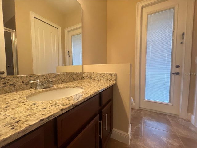 bathroom featuring toilet, a stall shower, vanity, and baseboards