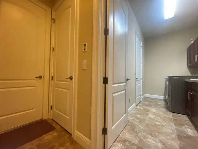 clothes washing area featuring cabinet space and baseboards