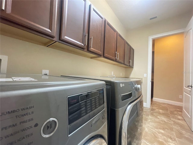 washroom featuring washer and dryer, cabinet space, visible vents, and baseboards