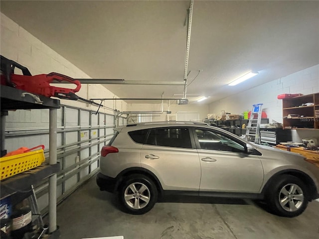 garage featuring a garage door opener and concrete block wall