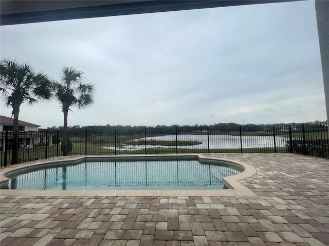 view of swimming pool featuring a patio, a water view, fence, and a fenced in pool