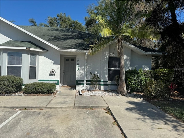 view of front of property with a shingled roof and stucco siding