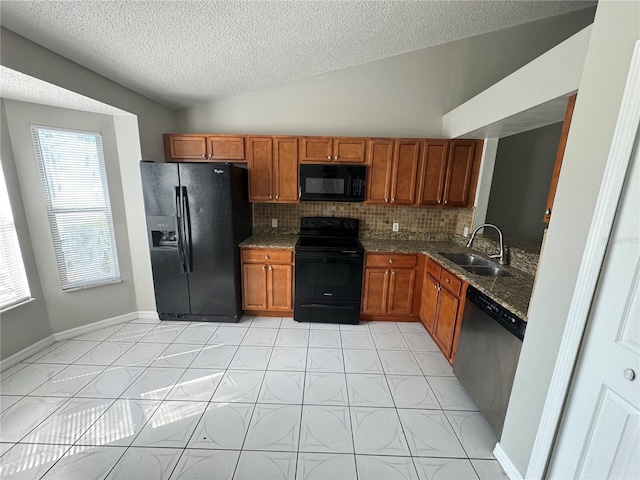 kitchen with vaulted ceiling, brown cabinets, a sink, and black appliances