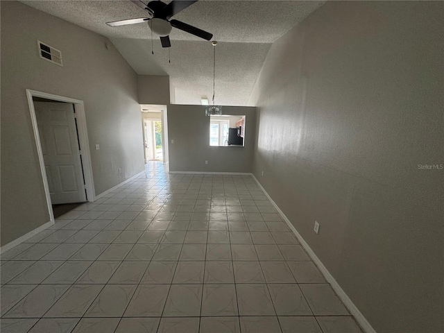 spare room featuring lofted ceiling, visible vents, a ceiling fan, light tile patterned flooring, and a textured ceiling