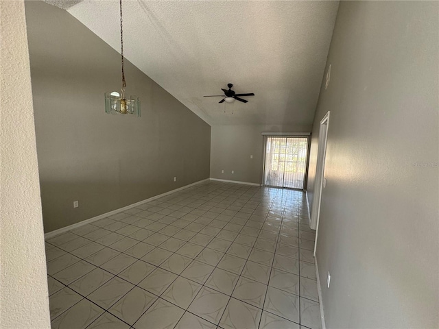 empty room featuring ceiling fan with notable chandelier, a textured ceiling, lofted ceiling, and baseboards