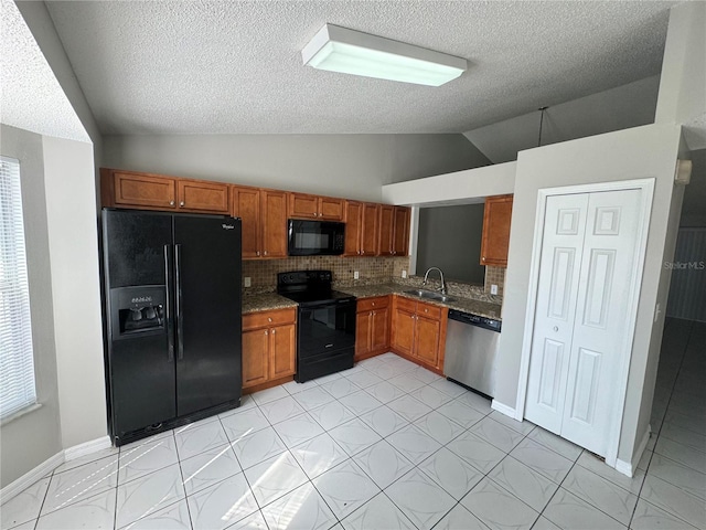 kitchen featuring lofted ceiling, a sink, black appliances, tasteful backsplash, and brown cabinetry