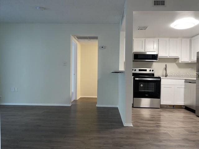 kitchen featuring sink, dark wood-type flooring, stainless steel appliances, and white cabinets