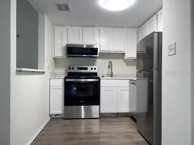 kitchen featuring white cabinetry, hardwood / wood-style floors, stainless steel appliances, and sink