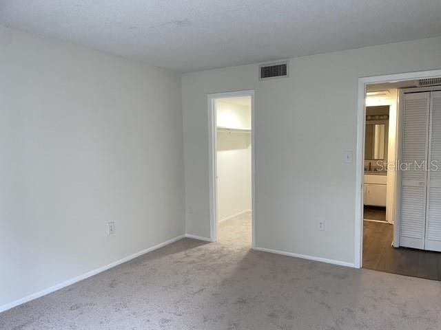 unfurnished bedroom with a walk in closet, light colored carpet, and a closet