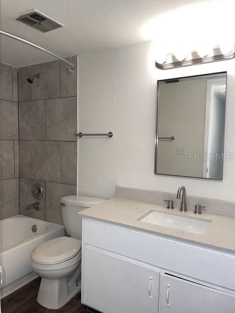 full bathroom with vanity, tiled shower / bath combo, toilet, and hardwood / wood-style flooring