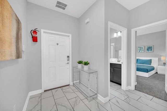 foyer entrance with visible vents, baseboards, and marble finish floor