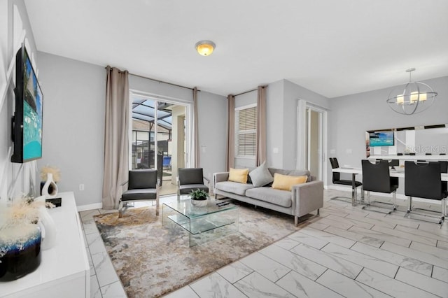 living area featuring marble finish floor, baseboards, and a chandelier