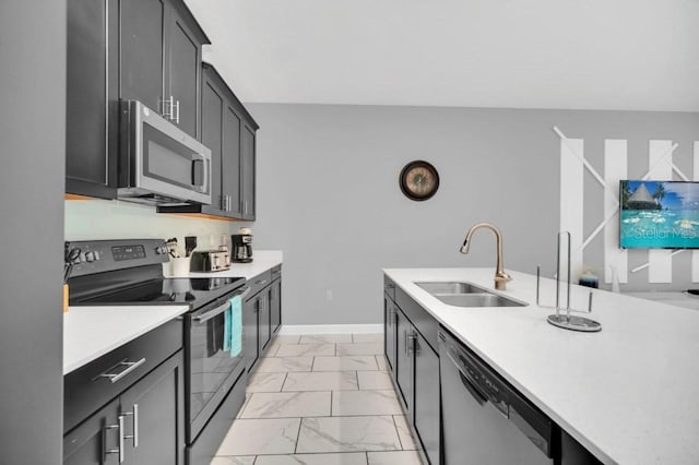 kitchen with stainless steel appliances, a sink, baseboards, marble finish floor, and light countertops