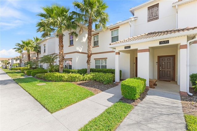 townhome / multi-family property featuring stucco siding, a residential view, and a tiled roof