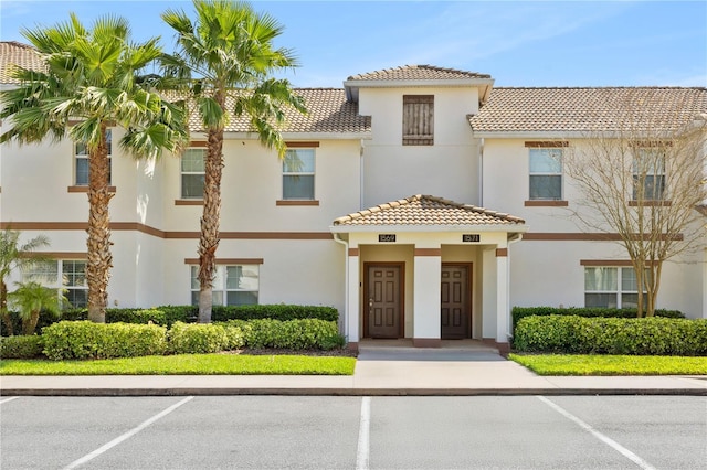 view of front of property with stucco siding, uncovered parking, and a tile roof