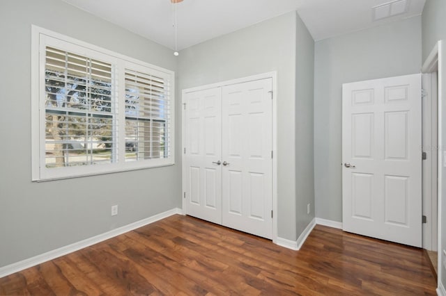 unfurnished bedroom with dark wood-type flooring and a closet