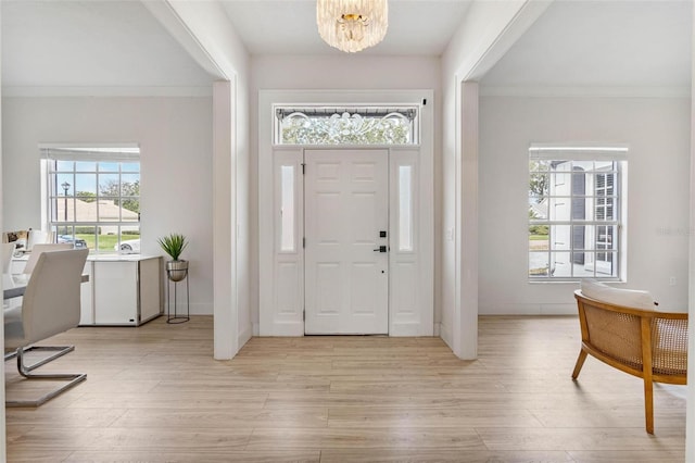 entryway with an inviting chandelier, light hardwood / wood-style flooring, and ornamental molding