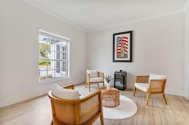 living area with crown molding and light hardwood / wood-style floors