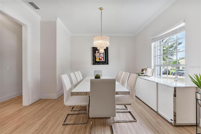 dining area featuring an inviting chandelier, ornamental molding, and light wood-type flooring