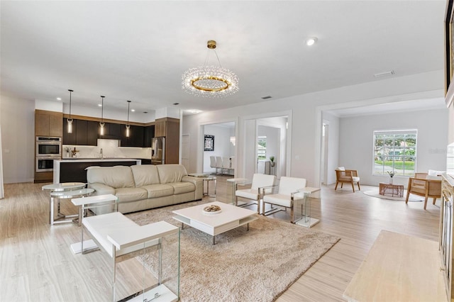 living room featuring sink, a chandelier, and light hardwood / wood-style flooring