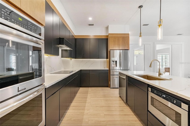 kitchen with sink, tasteful backsplash, hanging light fixtures, stainless steel appliances, and light stone countertops