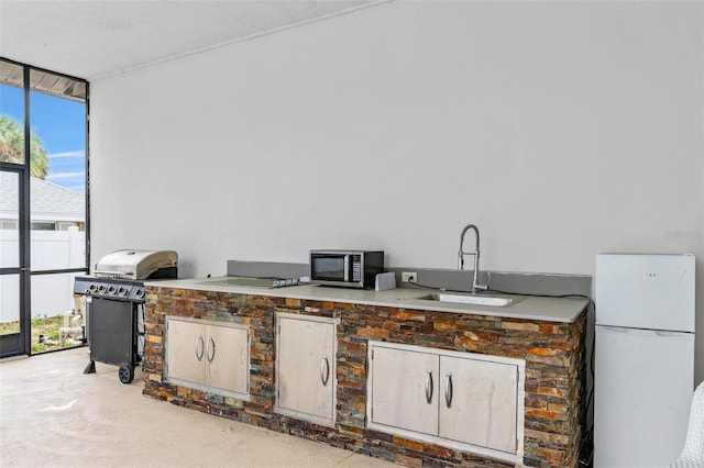 interior space with a wall of windows, sink, and white fridge