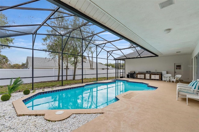 view of pool featuring exterior kitchen, a patio, and a lanai