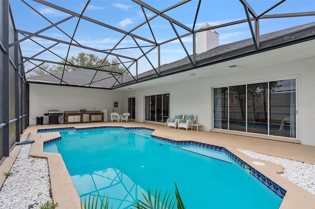 view of pool featuring an outdoor kitchen, a patio, and glass enclosure