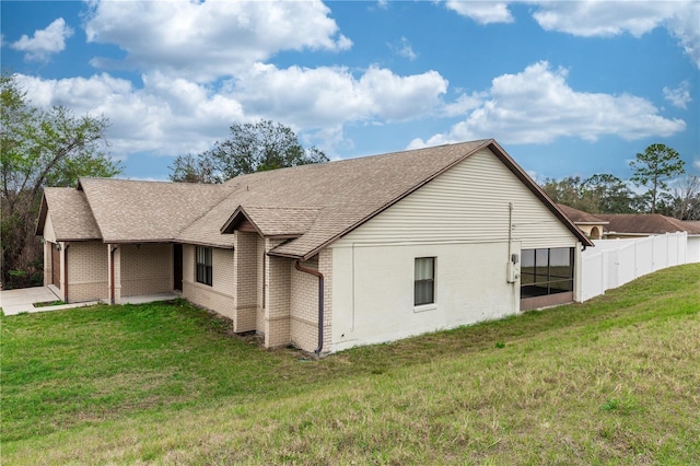 back of property featuring an attached garage, a shingled roof, fence, and a yard