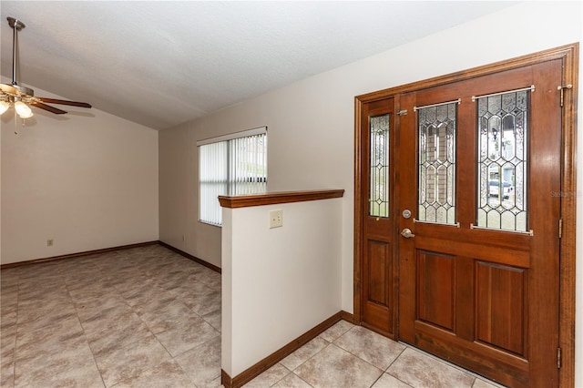 entryway with lofted ceiling, ceiling fan, a textured ceiling, and baseboards