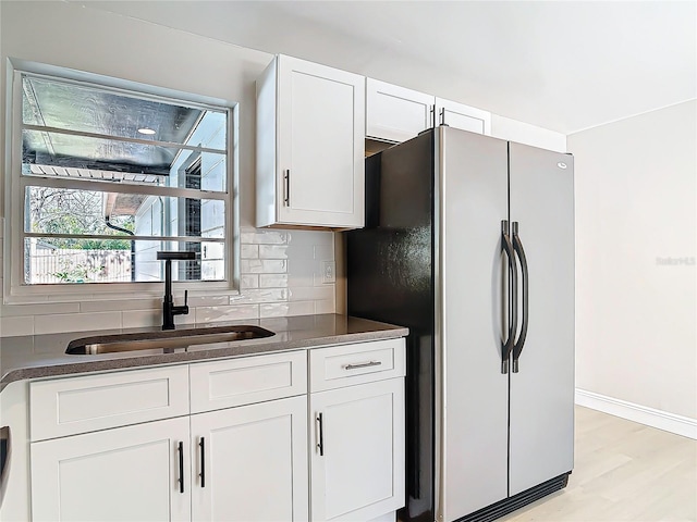 kitchen with sink, tasteful backsplash, stainless steel refrigerator, light hardwood / wood-style floors, and white cabinets