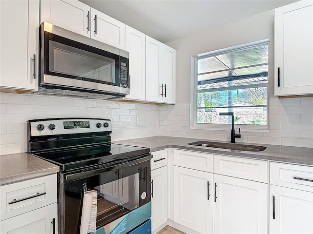 kitchen with white cabinetry, black electric range oven, sink, and tasteful backsplash