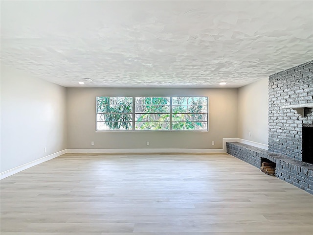 unfurnished living room with a fireplace, light hardwood / wood-style flooring, and a textured ceiling