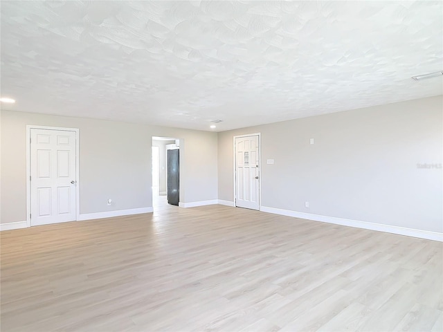 unfurnished room featuring light hardwood / wood-style floors and a textured ceiling