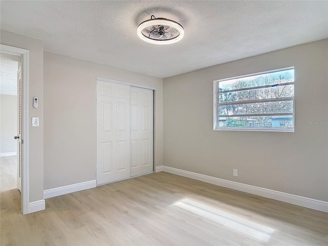 unfurnished bedroom with a closet, light hardwood / wood-style flooring, and a textured ceiling