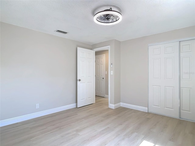 unfurnished bedroom featuring a closet, light hardwood / wood-style flooring, and a textured ceiling