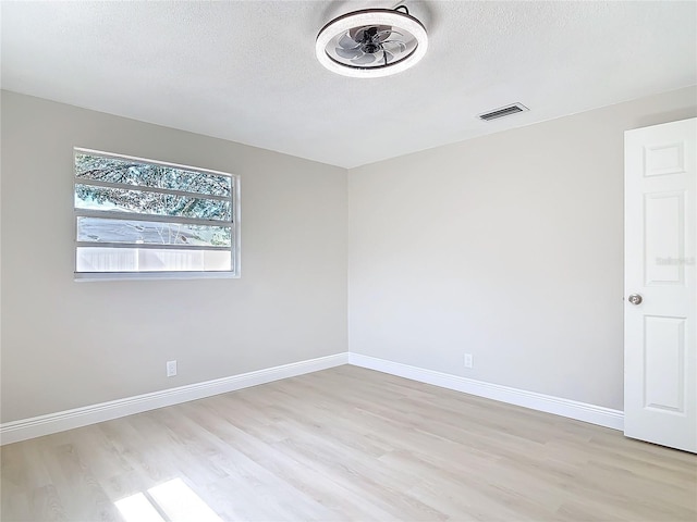 spare room with light hardwood / wood-style floors and a textured ceiling