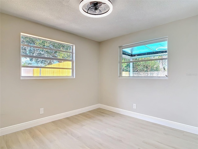 empty room with a textured ceiling and light hardwood / wood-style flooring