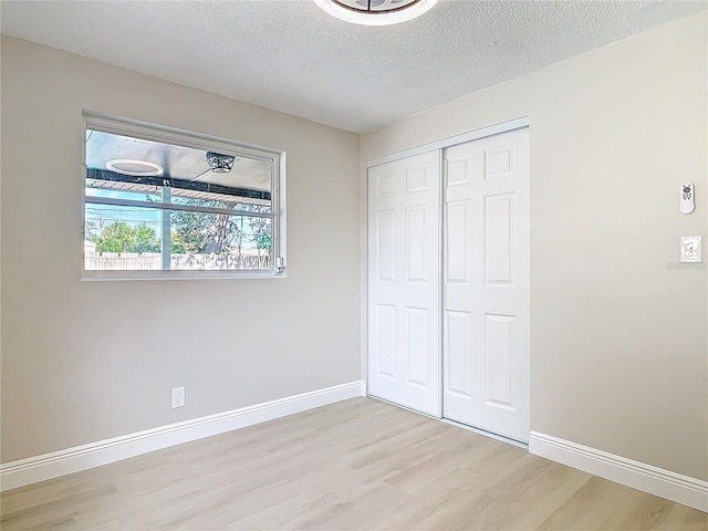 unfurnished bedroom featuring a textured ceiling, light wood-type flooring, and a closet