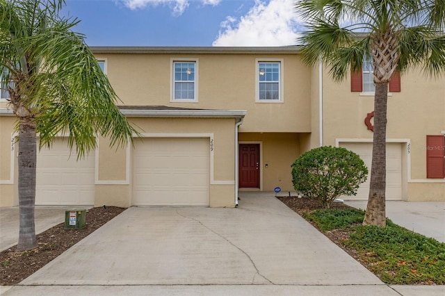 multi unit property with a garage, driveway, and stucco siding