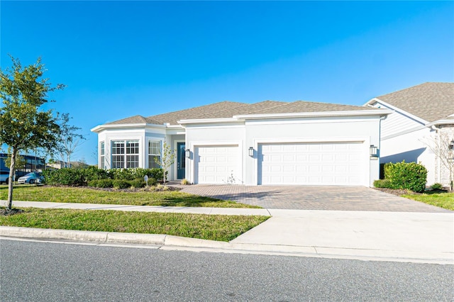 view of front of property featuring a garage, driveway, a shingled roof, and stucco siding