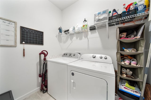 clothes washing area featuring laundry area, washer and clothes dryer, baseboards, and light tile patterned floors