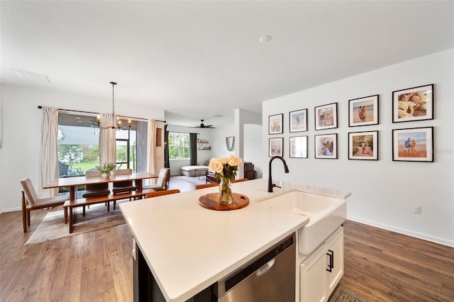 kitchen with white cabinetry, light countertops, dishwasher, a center island with sink, and pendant lighting