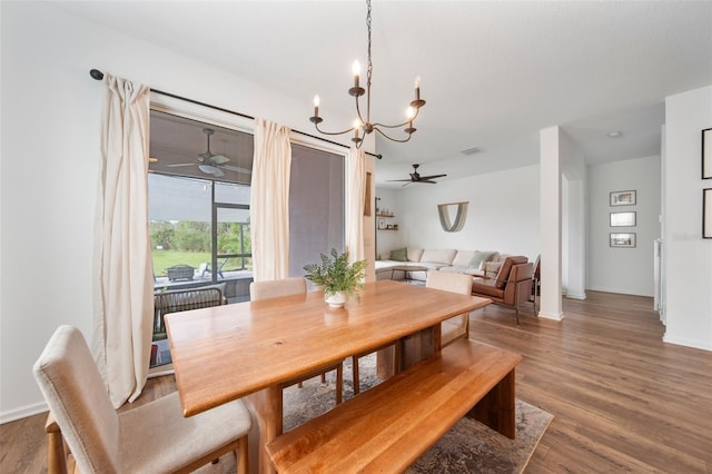 dining space featuring dark wood-style flooring, baseboards, and ceiling fan with notable chandelier