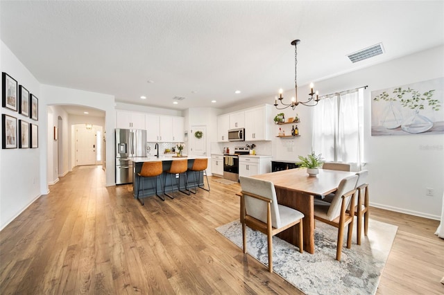 dining space featuring arched walkways, recessed lighting, visible vents, light wood-style flooring, and baseboards