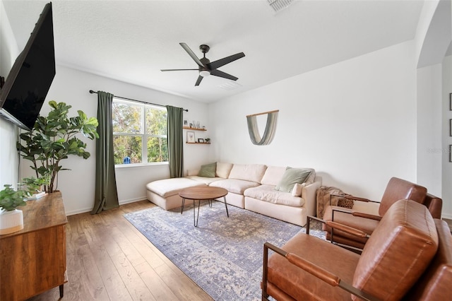 living area featuring light wood-type flooring, visible vents, ceiling fan, and baseboards